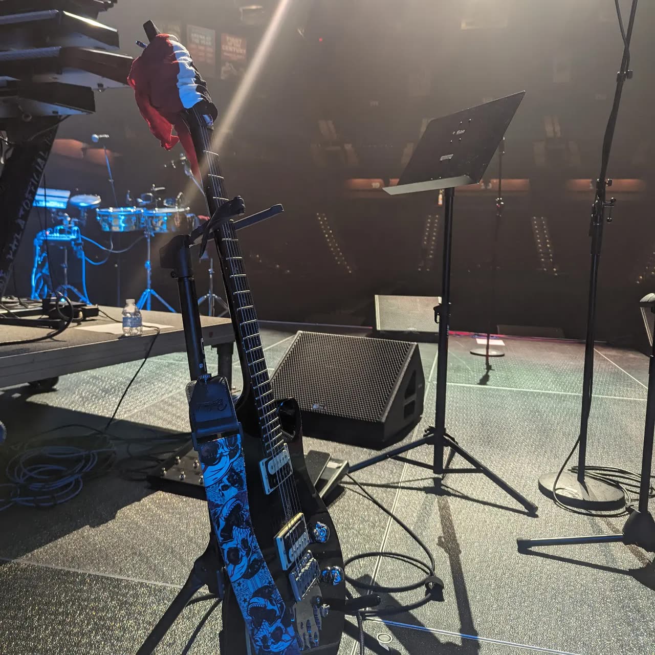 A bass guitar, stands and monitors set up on stage.