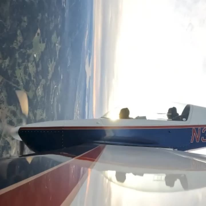 The wing of the Extra 300L over terrain in flight, registration partly visible.