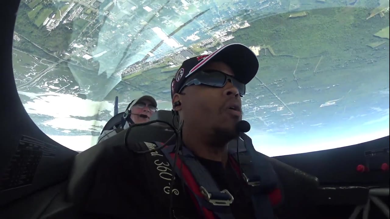 Doug Byrd inverted in the Extra 300L, town and river filling the canopy overhead, a second occupant seated behind him.